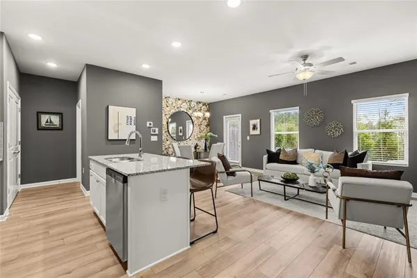 a kitchen with stainless steel appliances granite countertop a refrigerator a stove top oven a sink dishwasher and white cabinets with wooden floor