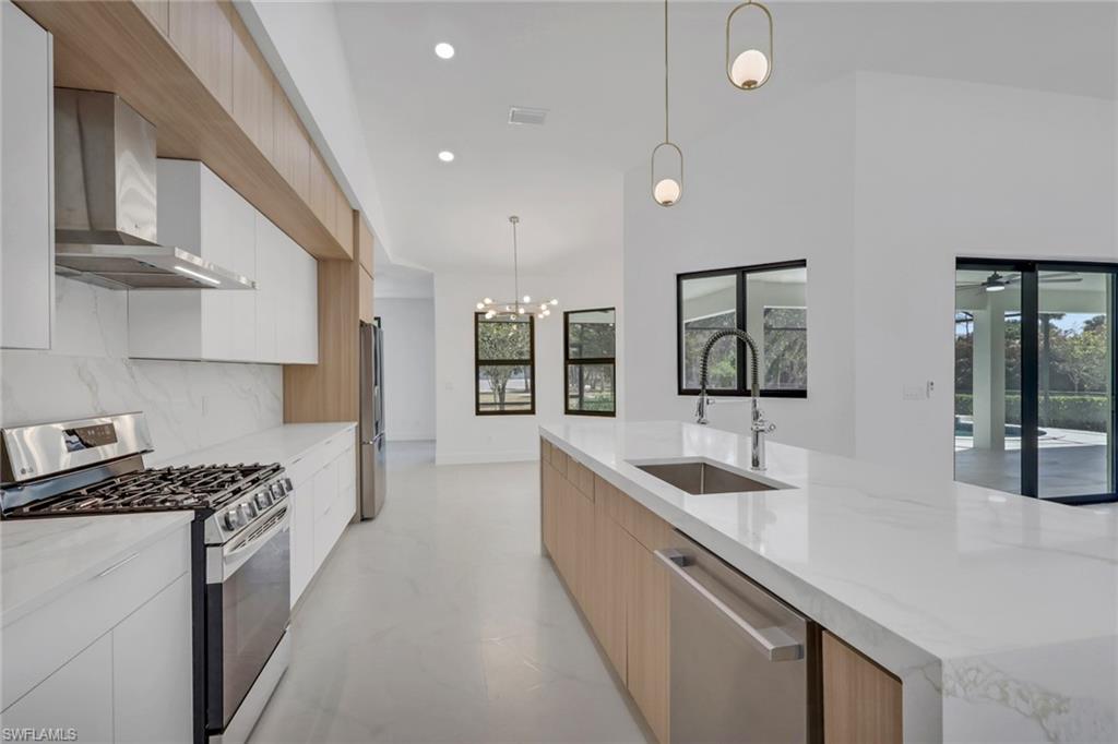 730 29th Street Southwest Naples, FL 34117 - Photo 18 of 50 Kitchen featuring two tone color scheme, stainless steel appliances, modern cabinets, light stone counters, and hanging lights