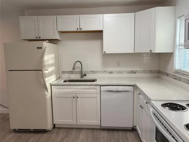 a kitchen with white cabinets and white appliances