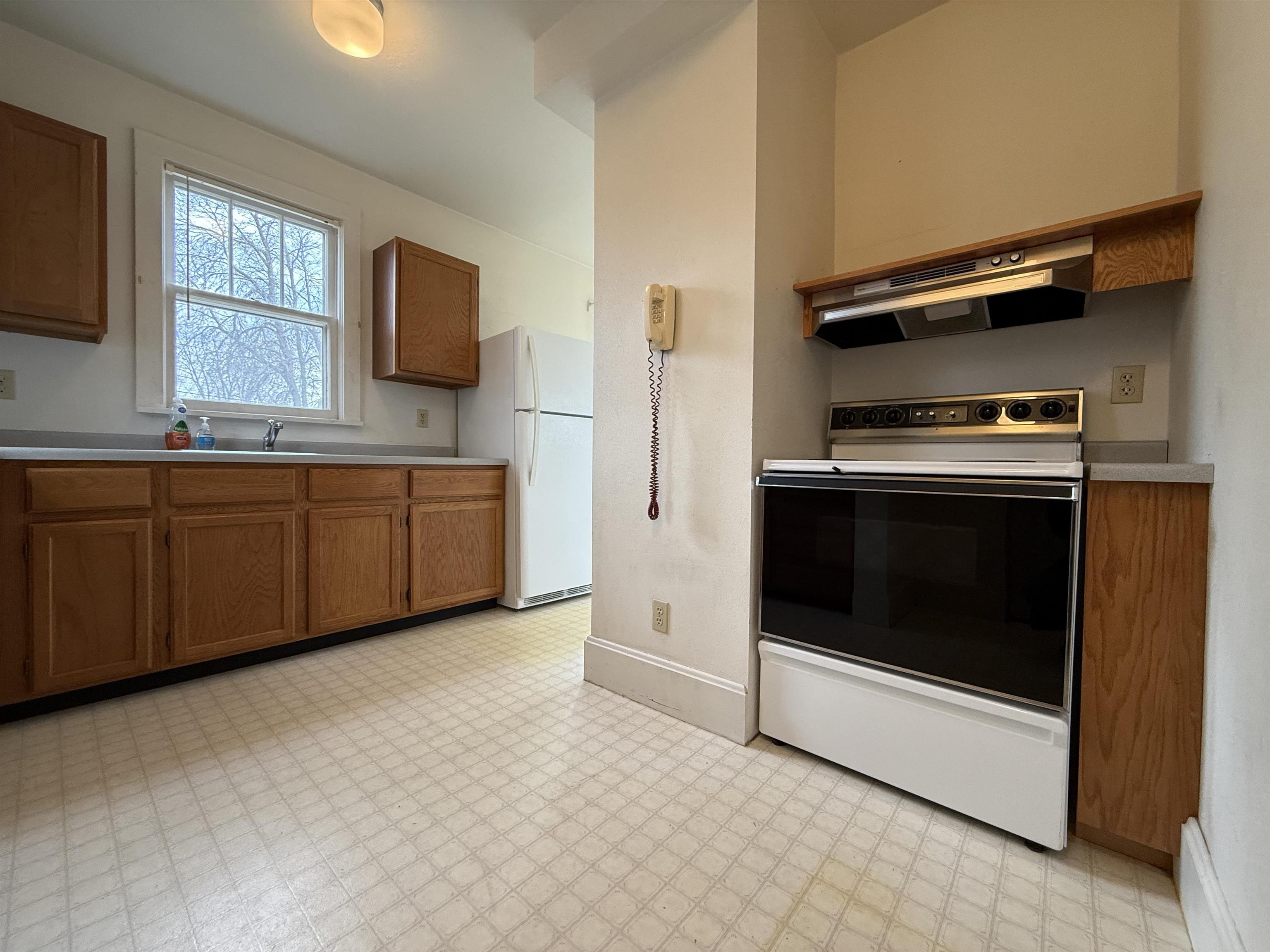 214 8th Street Southwest Chisholm, MN 55719 - Photo 9 of 25 Kitchen featuring brown cabinetry, white appliances, light floors, and light countertops