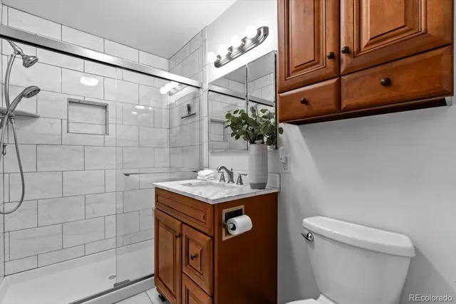 a bathroom with a granite countertop sink a toilet and shower