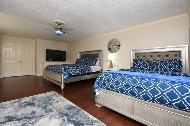 a bedroom with a bed chairs and wooden floor