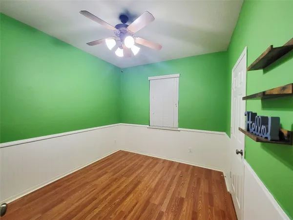 an empty room with wooden floor and fan