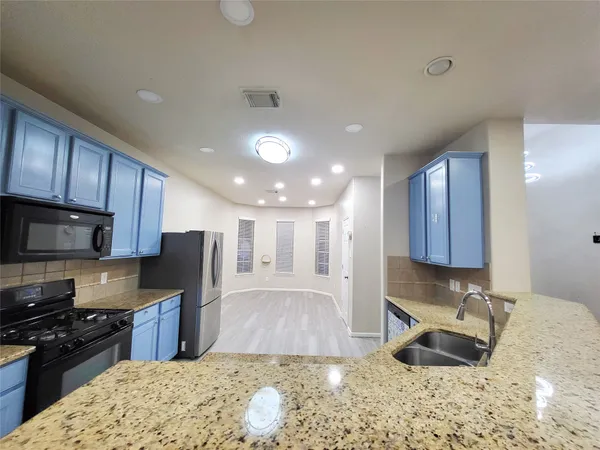 a kitchen with stainless steel appliances granite countertop a sink refrigerator stove microwave and cabinets