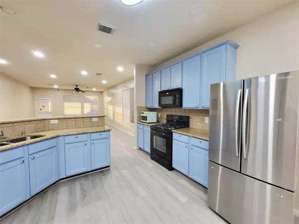 a large kitchen with stainless steel appliances granite countertop a refrigerator sink and stove