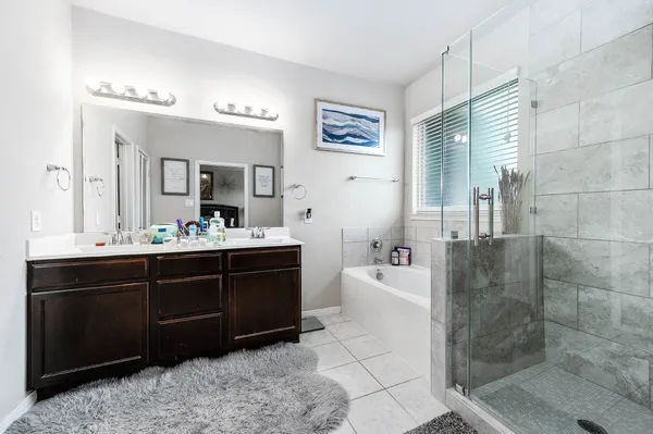 a bathroom with a bathtub mirror and double sink