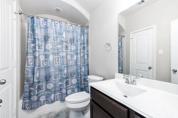 a bathroom with a sink a toilet and shower curtain