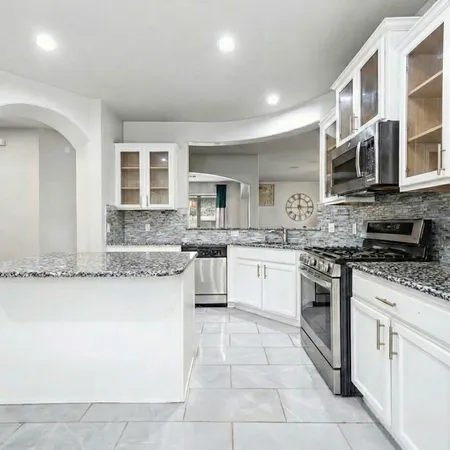 a large kitchen with stainless steel appliances granite countertop a stove and cabinets