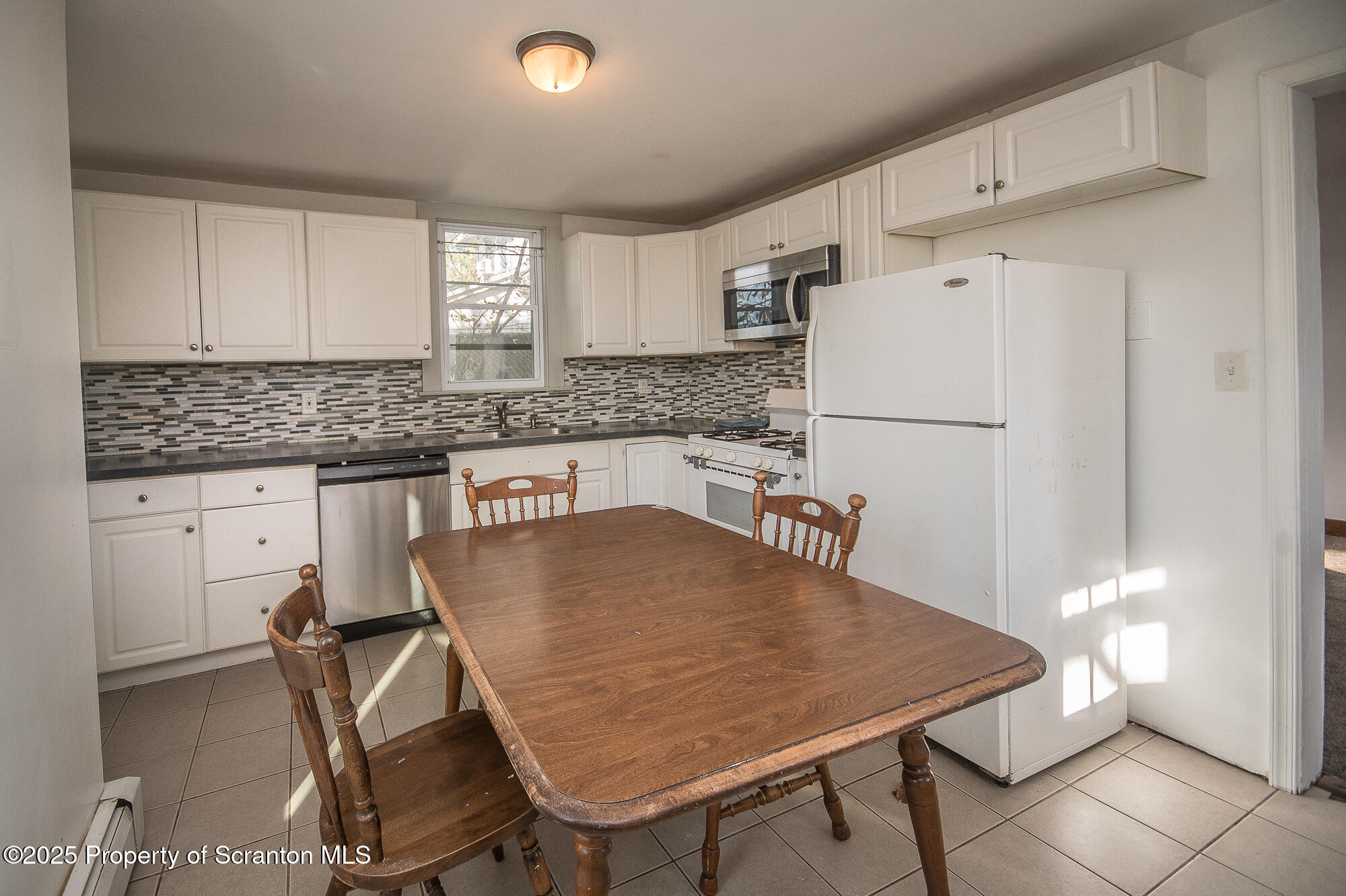 1227 Rundle Street Scranton, PA 18504 - Photo 24 of 43 a kitchen with stainless steel appliances granite countertop a stove a refrigerator a sink a dining table and chairs