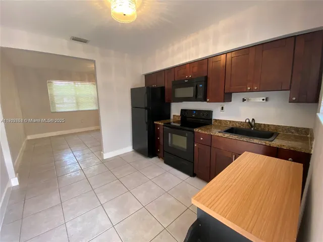 a kitchen with stainless steel appliances a stove a sink a chimney a refrigerator and cabinets