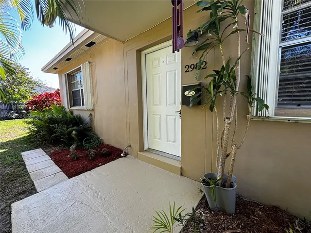 a vase of flowers sitting on a floor in front of a house
