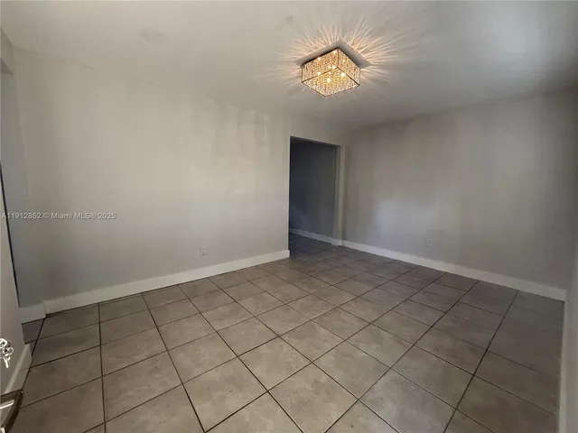 a view of an empty room and chandelier fan