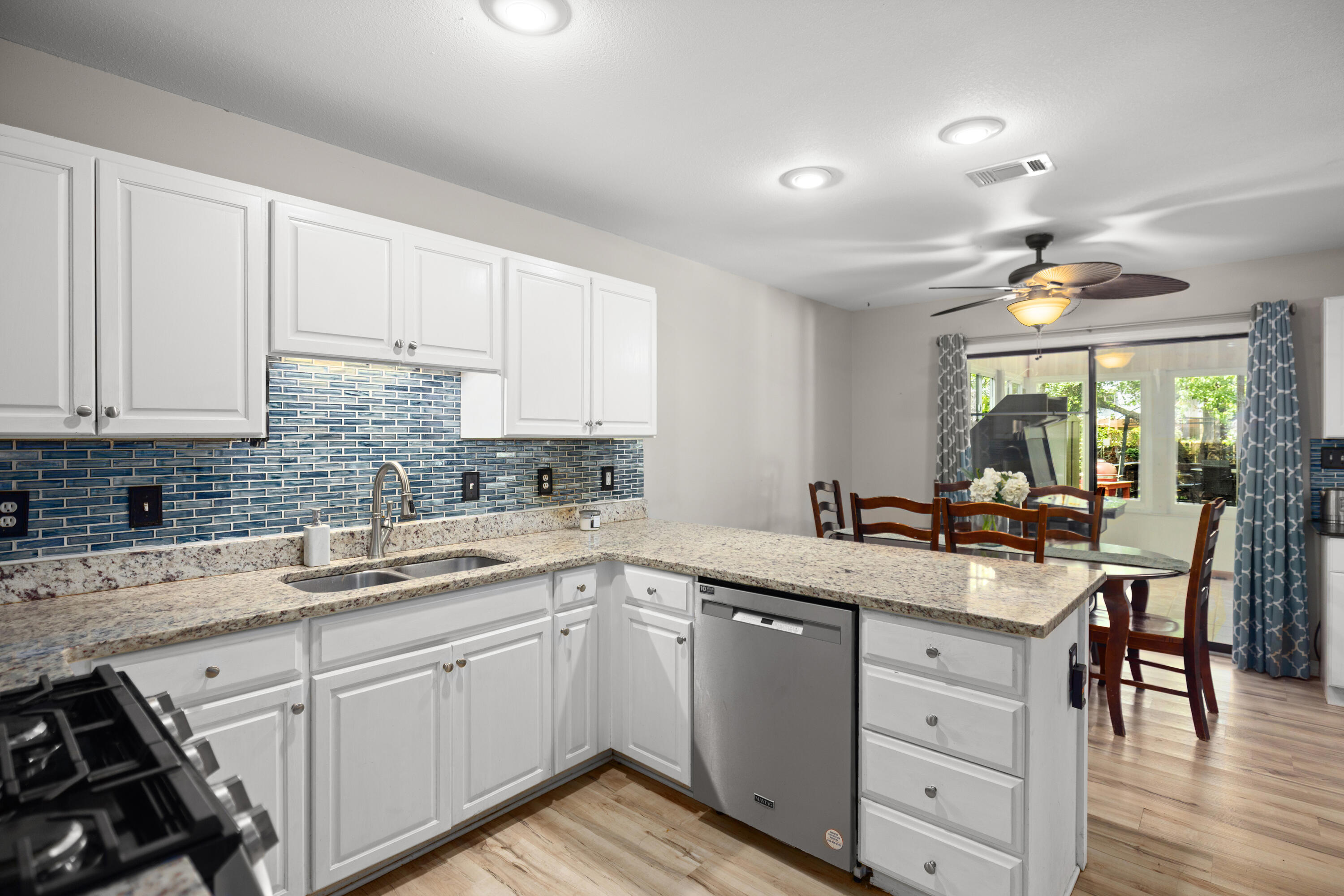314 Ruckel Drive Niceville, FL 32578 - Photo 23 of 66 a kitchen with a sink dishwasher a stove and white cabinets with wooden floor