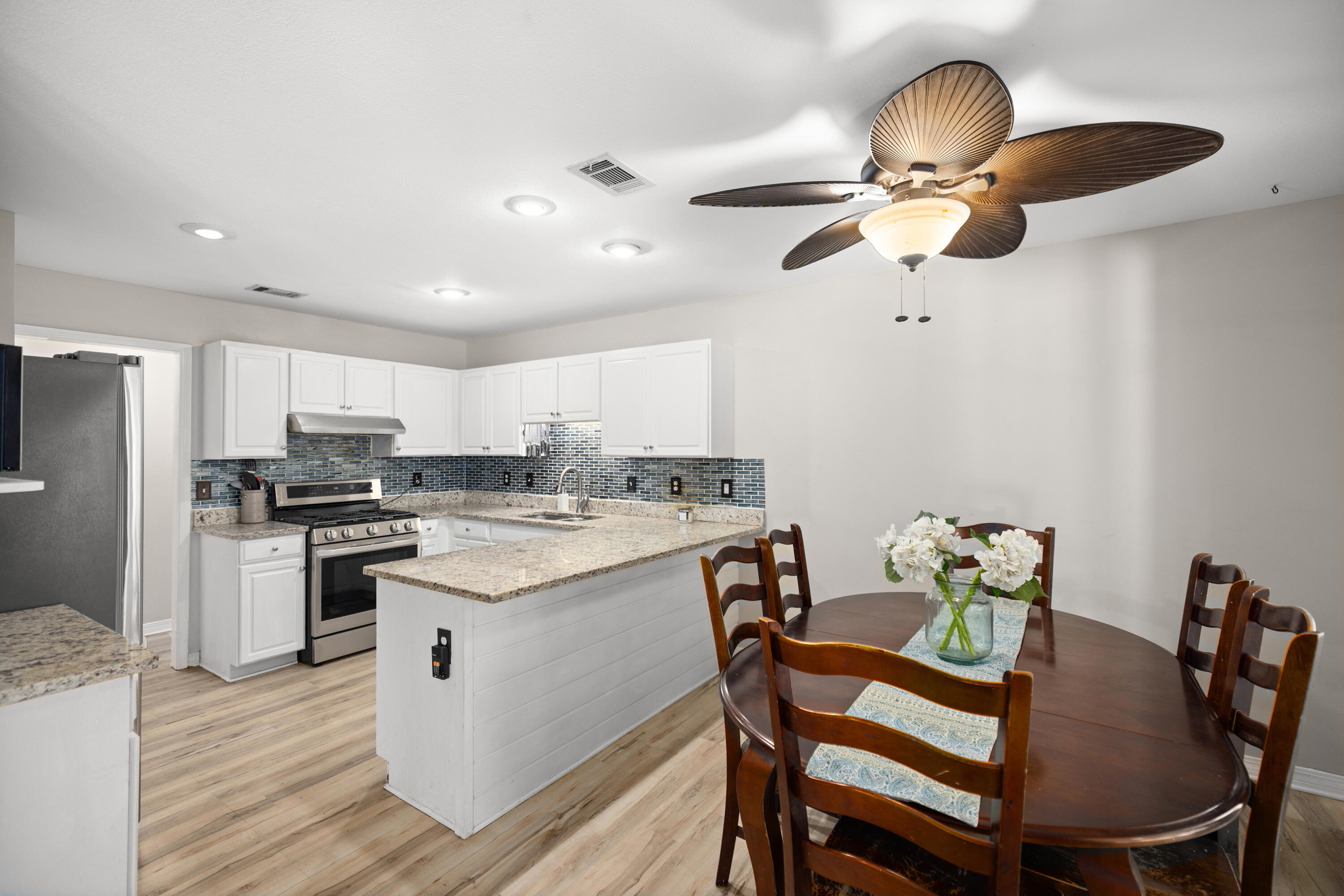 314 Ruckel Drive Niceville, FL 32578 - Photo 25 of 66 a kitchen with stainless steel appliances kitchen island granite countertop a dining table chairs and white cabinets