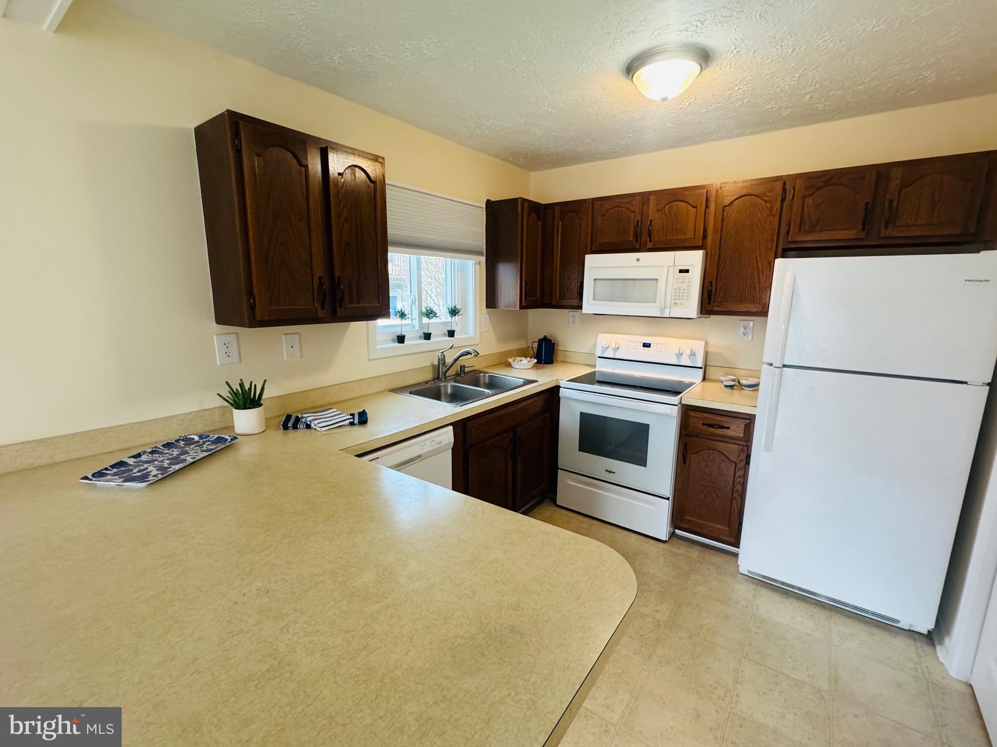 14400 Jarvis Avenue, Unit 113C Ocean City, MD 21842 - Photo 5 of 19 a kitchen with stainless steel appliances a refrigerator sink and microwave