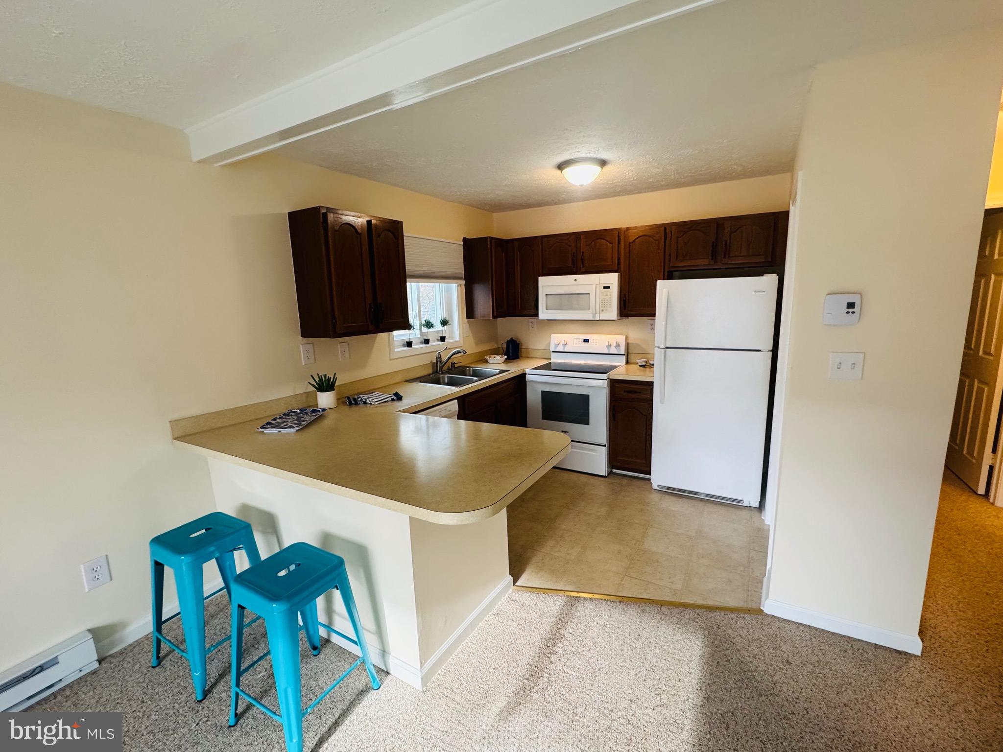 14400 Jarvis Avenue, Unit 113C Ocean City, MD 21842 - Photo 7 of 19 a kitchen with stainless steel appliances a sink a stove a refrigerator and a refrigerator