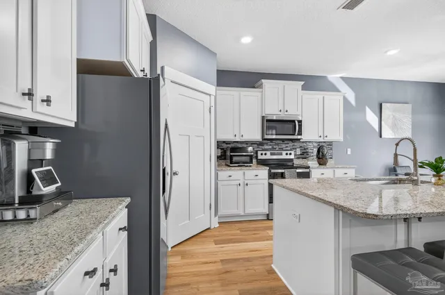 a kitchen with stainless steel appliances kitchen island granite countertop a stove refrigerator and cabinets