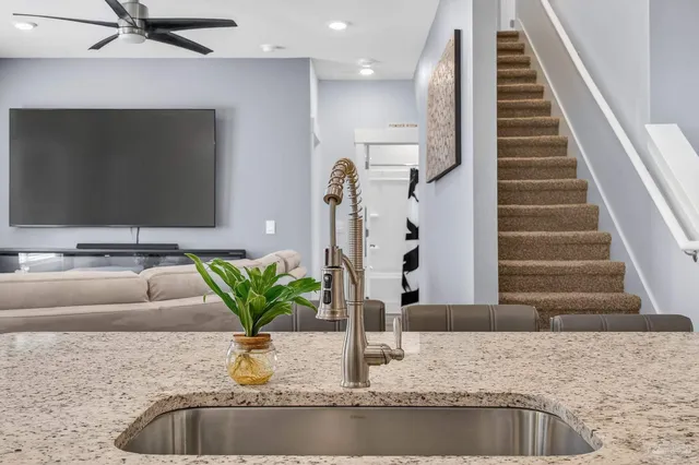 a kitchen with stainless steel appliances granite countertop a stove top oven a sink dishwasher and white cabinets with wooden floor