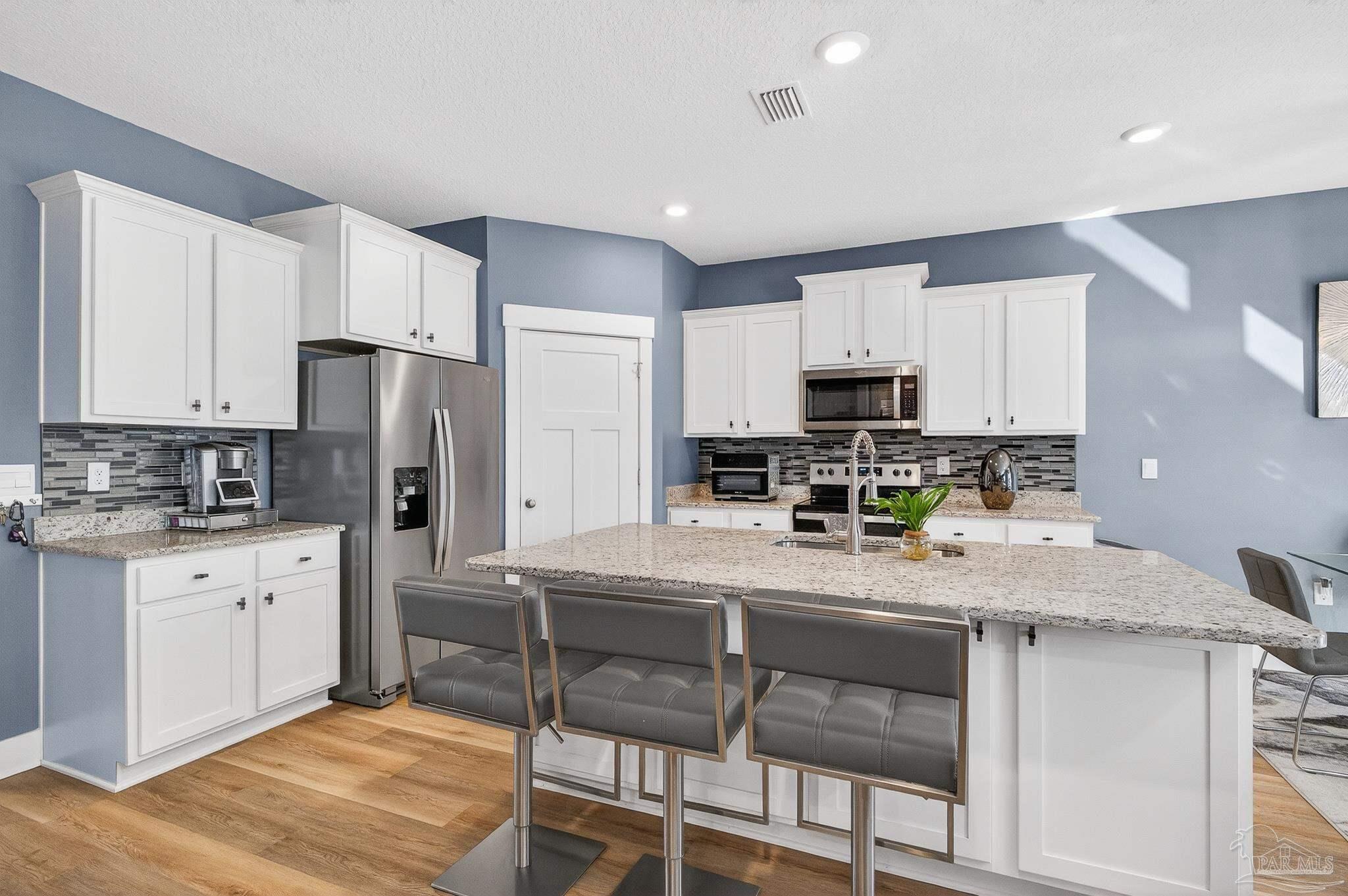 6076 Rutherford Loop Pensacola, FL 32526 - Photo 19 of 67 a kitchen with stainless steel appliances granite countertop a stove a sink a refrigerator white cabinets and wooden floor