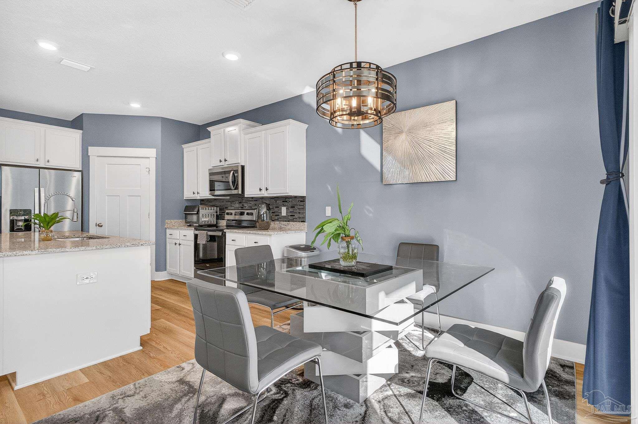 6076 Rutherford Loop Pensacola, FL 32526 - Photo 21 of 67 a kitchen with stainless steel appliances granite countertop a stove top oven a sink dishwasher and white cabinets with wooden floor