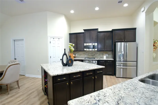 a kitchen with stainless steel appliances kitchen island granite countertop a sink refrigerator and cabinets