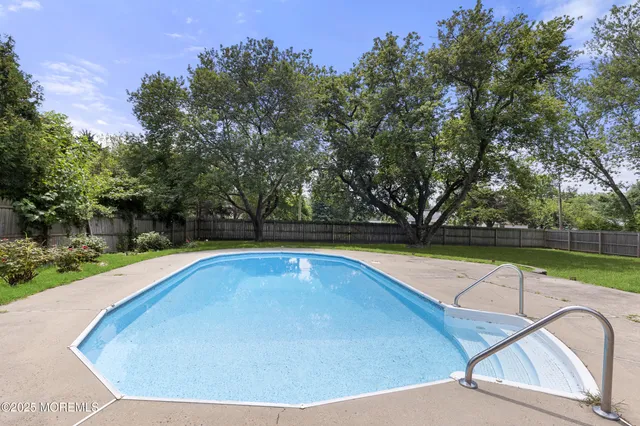 a view of swimming pool with seating area and trees in the background