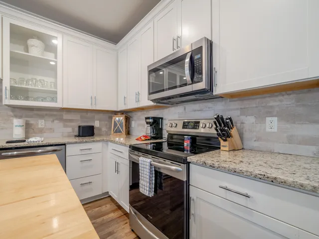 a kitchen with stainless steel appliances granite countertop a stove a sink and a microwave