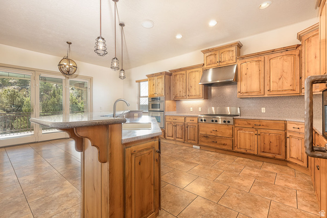888 East Fiddlers Canyon Road Cedar City, UT 84721 - Photo 16 of 74 Kitchen featuring a kitchen island with sink, a kitchen breakfast bar, tasteful backsplash, hanging light fixtures, and stainless steel appliances