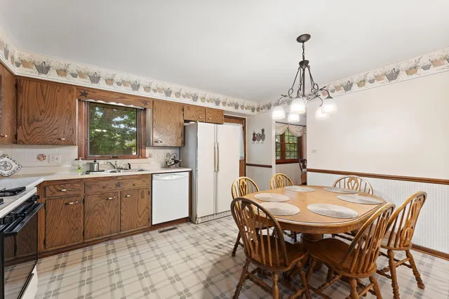 a kitchen with a dining table chairs and refrigerator