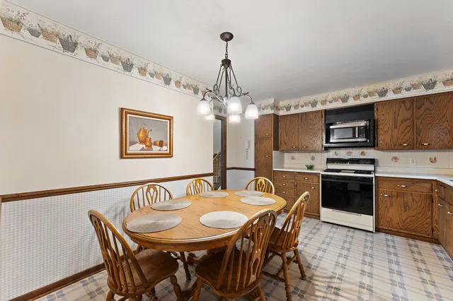 a kitchen with stainless steel appliances granite countertop a dining table and chairs a refrigerator with wooden floor