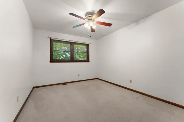 an empty room with windows and ceiling fan