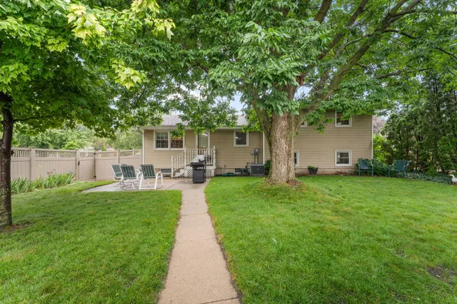 a view of a patio with table and chairs and potted plants and large trees