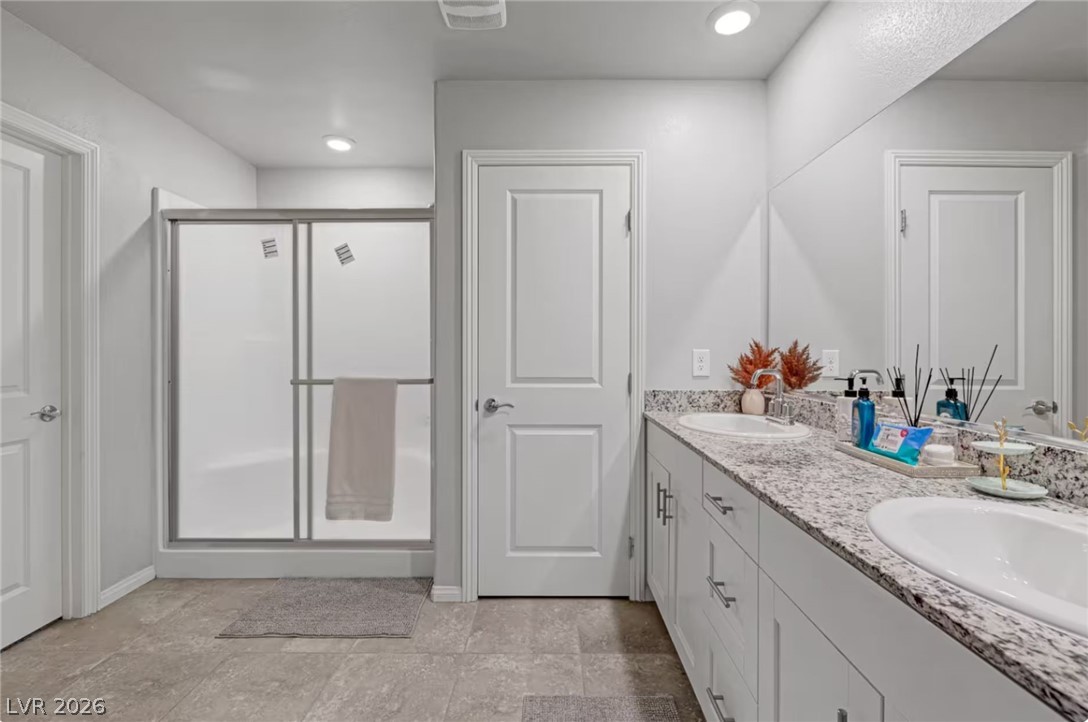 8244 Selenite Street Las Vegas, NV 89113 - Photo 13 of 16 This modern bathroom features a spacious shower and a vanity with dual sinks.