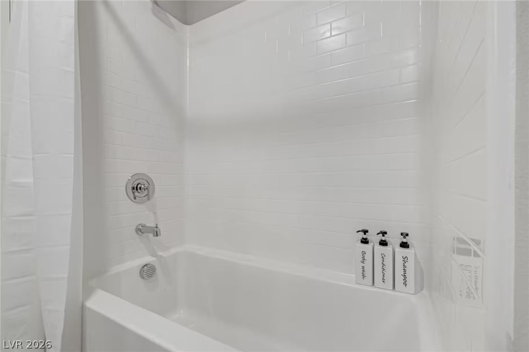 8244 Selenite Street Las Vegas, NV 89113 - Photo 15 of 16 This bright bathroom features subway tile, a bathtub with a shower, and sleek fixtures.