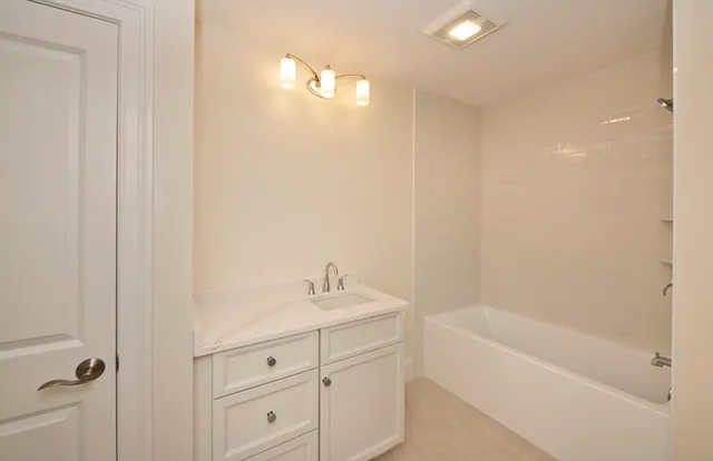 a bathroom with a tub sink vanity and a mirror