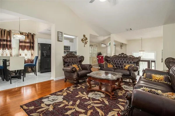 a living room with furniture and a dining table with wooden floor