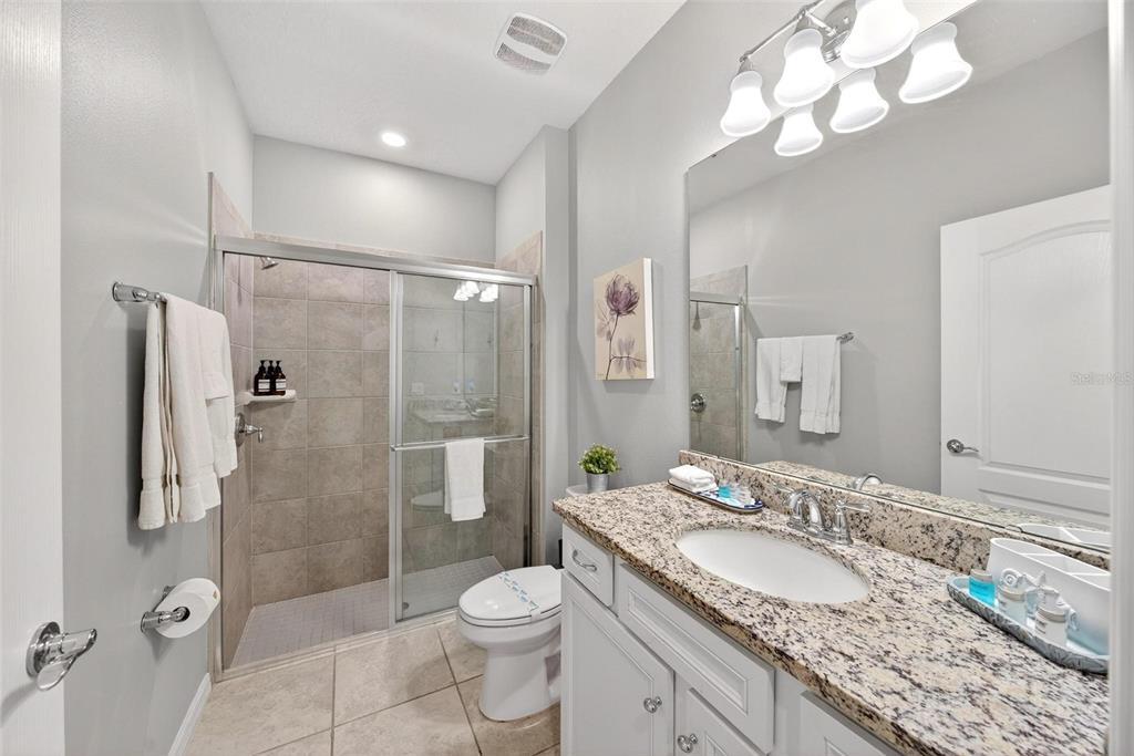 7554 Oak Spring Lane Davenport, FL 33837 - Photo 27 of 74 a bathroom with a granite countertop sink a toilet a mirror and shower
