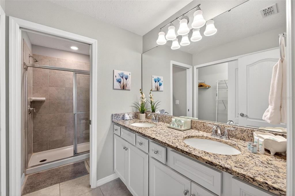 7554 Oak Spring Lane Davenport, FL 33837 - Photo 37 of 74 a bathroom with a granite countertop shower sink and mirror