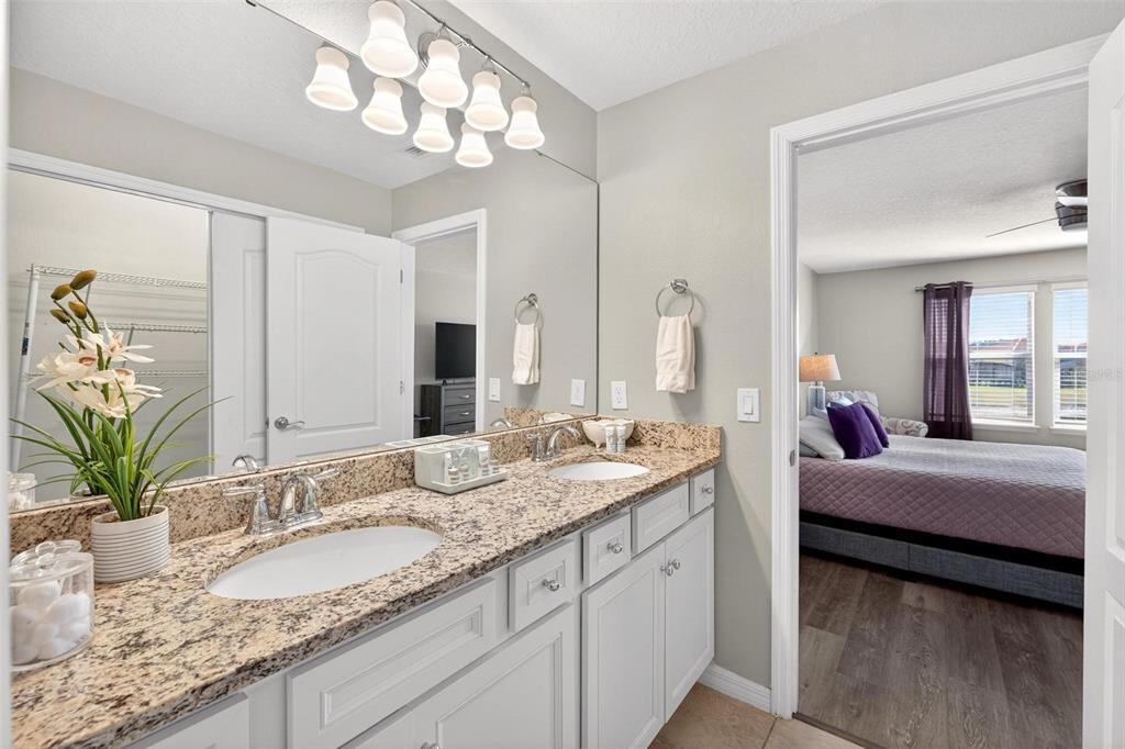 7554 Oak Spring Lane Davenport, FL 33837 - Photo 38 of 74 a en suite bathroom with a granite countertop sink and a mirror