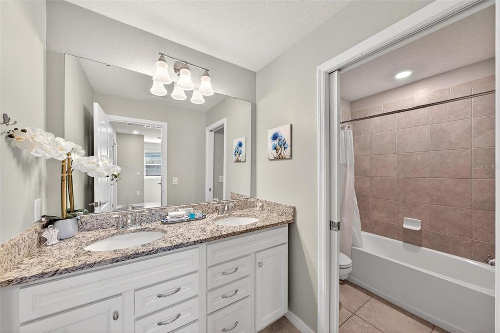 7554 Oak Spring Lane Davenport, FL 33837 - Photo 49 of 74 a bathroom with a granite countertop sink mirror and a bathtub