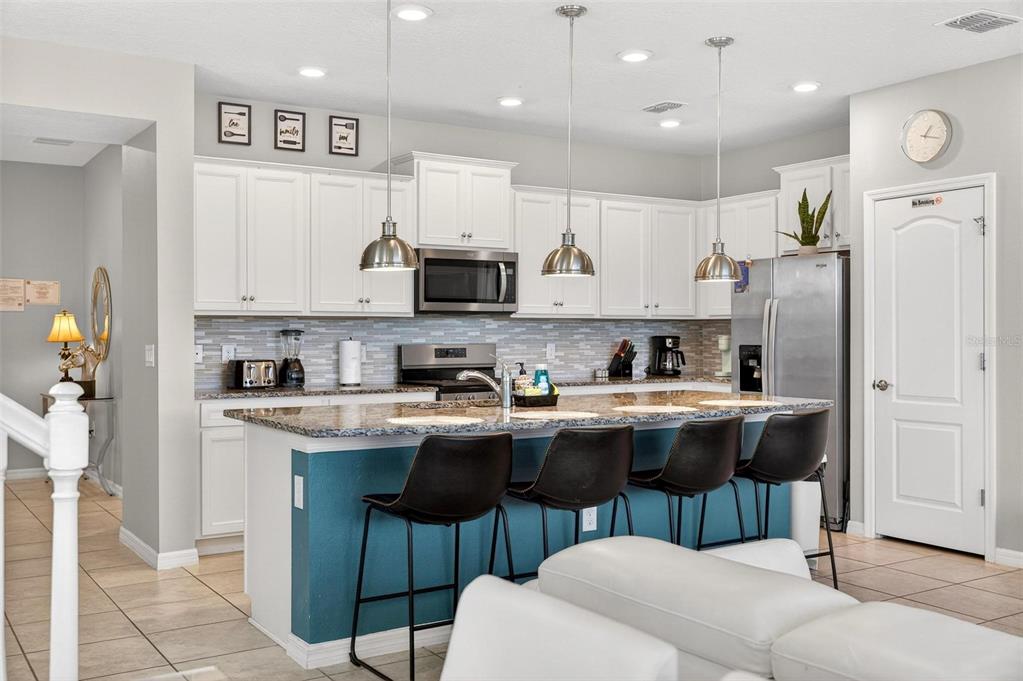 7554 Oak Spring Lane Davenport, FL 33837 - Photo 7 of 74 a kitchen with stainless steel appliances granite countertop a stove a sink a refrigerator and white cabinets with wooden floors