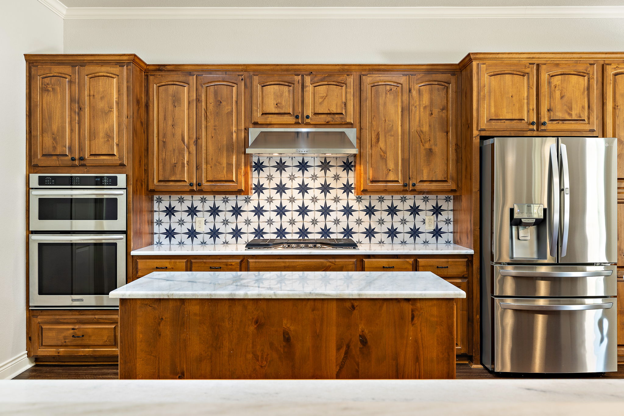 231 Marbella Way Georgetown, TX 78633 - Photo 9 of 40 A well-appointed kitchen features rich wood cabinetry, patterned tile backsplash, and high-end stainless steel appliances.