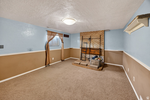 1218 East 100 South Logan, UT 84321 - Photo 22 of 23 Carpeted room featuring a brick fireplace with a raised hearth, a window with horizontal blinds, and a two-tone wall treatment with a chair rail