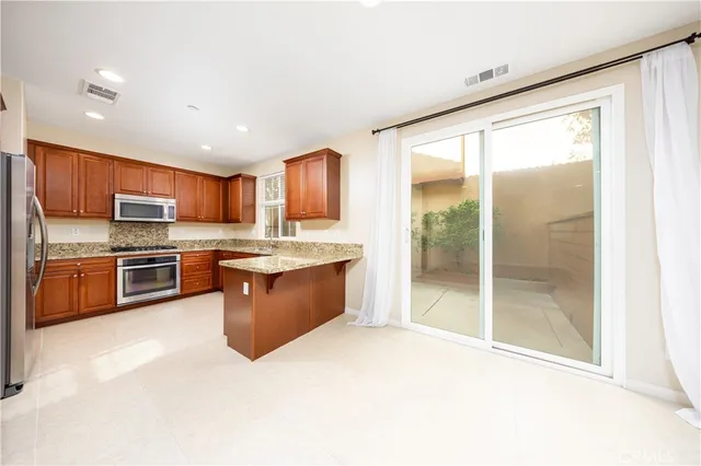 a large kitchen with stainless steel appliances granite countertop a stove a sink and a refrigerator