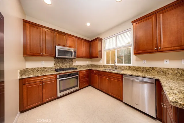 a kitchen with stainless steel appliances granite countertop wooden cabinets a stove top oven a sink and dishwasher