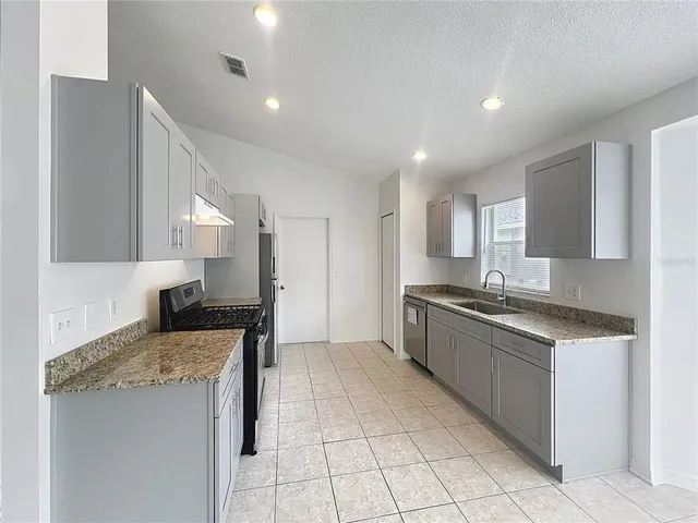 a large kitchen with stainless steel appliances granite countertop a stove and a sink