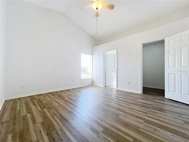 a view of empty room with wooden floor and fan