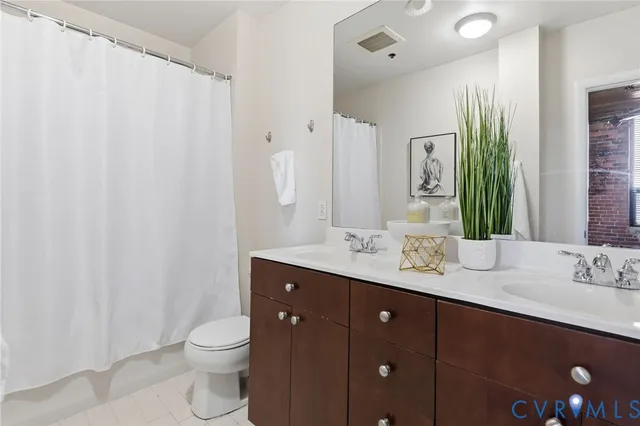 a bathroom with a double vanity sink toilet and a mirror