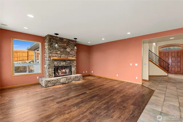 an empty room with wooden floor fireplace and windows