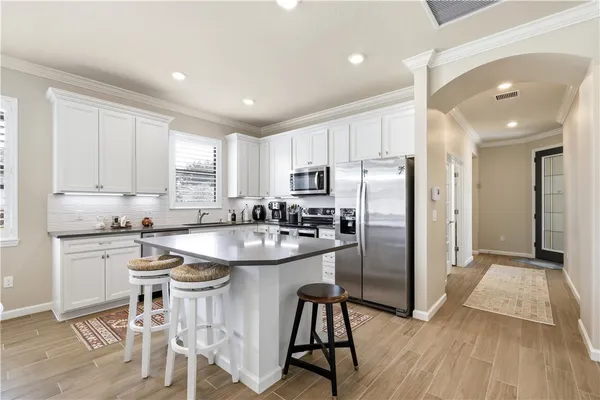 a kitchen with stainless steel appliances granite countertop a white cabinets and wooden floor